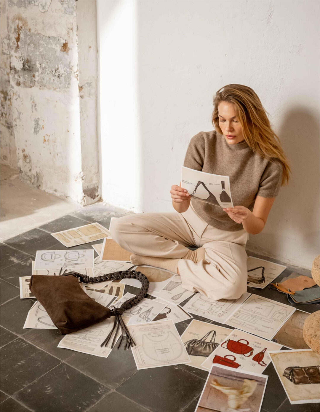 A designer reviewing bag patterns on the studio floor