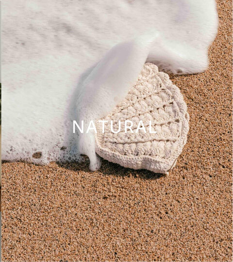 A crocheted bag on the sand at the water’s edge